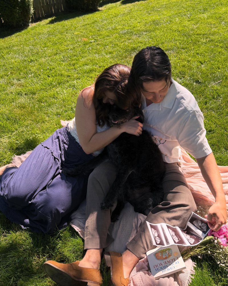 Joseph, Mandy, and their dog snuggled on a picnic blanket